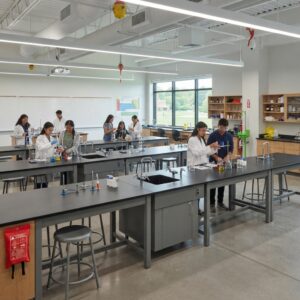 Comprehensive view of a science teaching lab with students at chemical resistant science lab tables, featuring safety equipment and abundant natural light