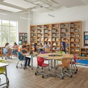 Dynamic school library setting showcasing school library bookshelves, students seated on ergonomic school chairs, and collaborative workstations with modern connectivity features